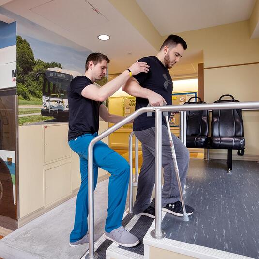 Patient in rehab simulating walking onto a bus Patient in rehab simulating walking onto a bus