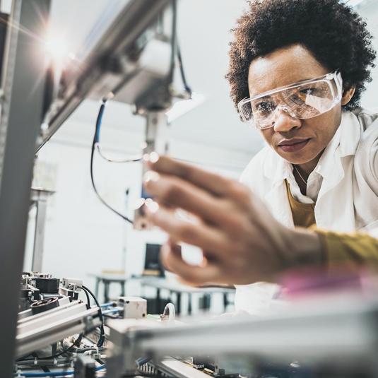 Image of a person working with a robotic device in a lab. Image of a person working with a robotic device in a lab.