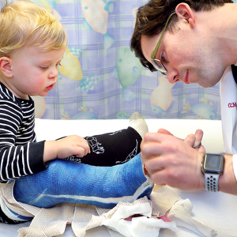 a doctor examining a child's cast on their leg